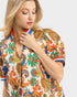 Woman wearing a colorful patterned shirt on a light gray background