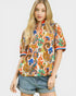 Woman wearing a colorful patterned shirt and denim shorts on a white background