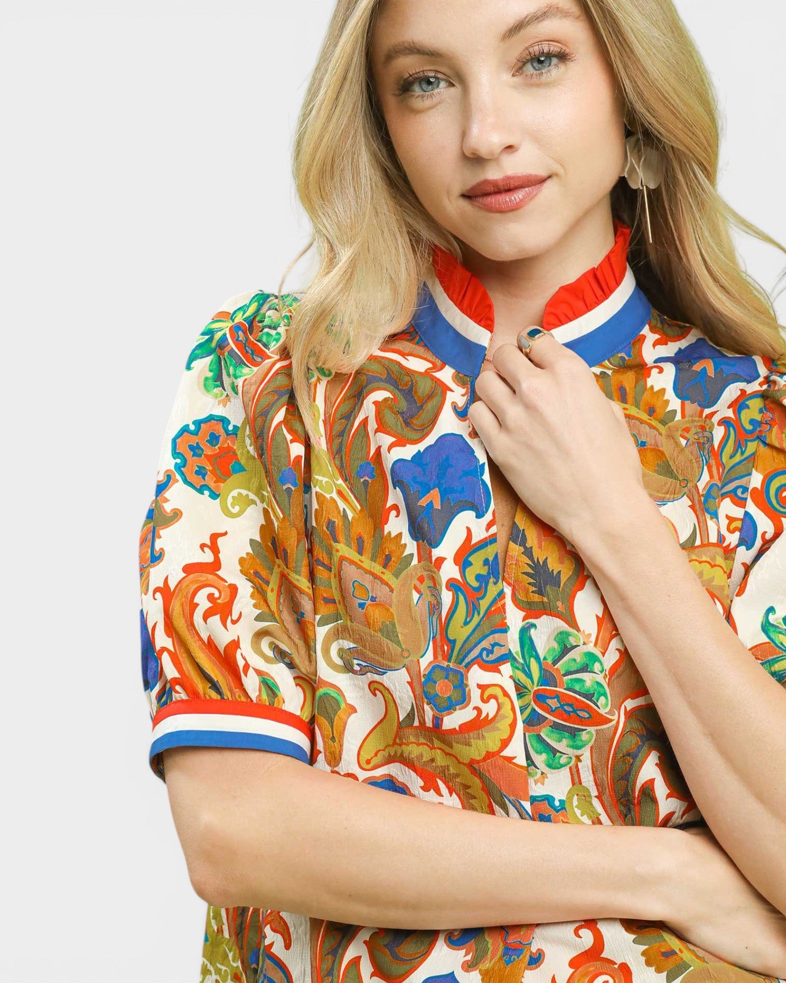 Woman wearing a colorful patterned top with a plain background