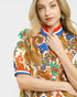 Woman wearing a colorful patterned top with a plain background