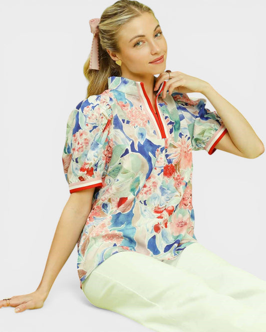 Woman wearing a colorful floral blouse with a plain background