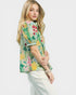 Woman wearing a colorful floral blouse against a white background