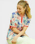Woman wearing a colorful floral shirt with a white background