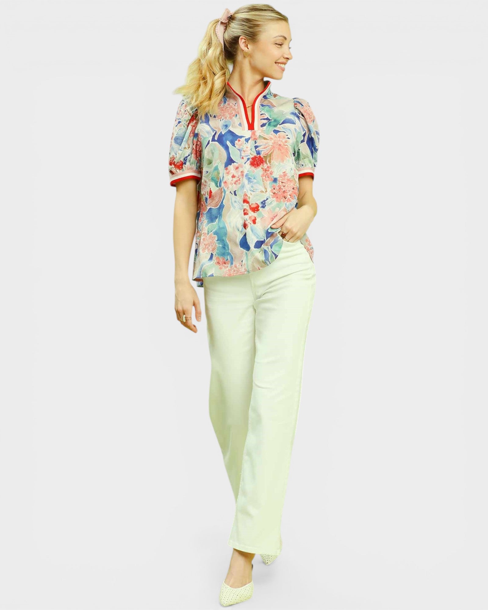 Woman wearing a floral blouse and light pants on a white background