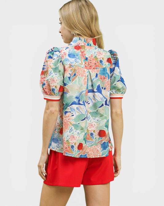 Woman wearing a colorful floral shirt and red shorts on a white background