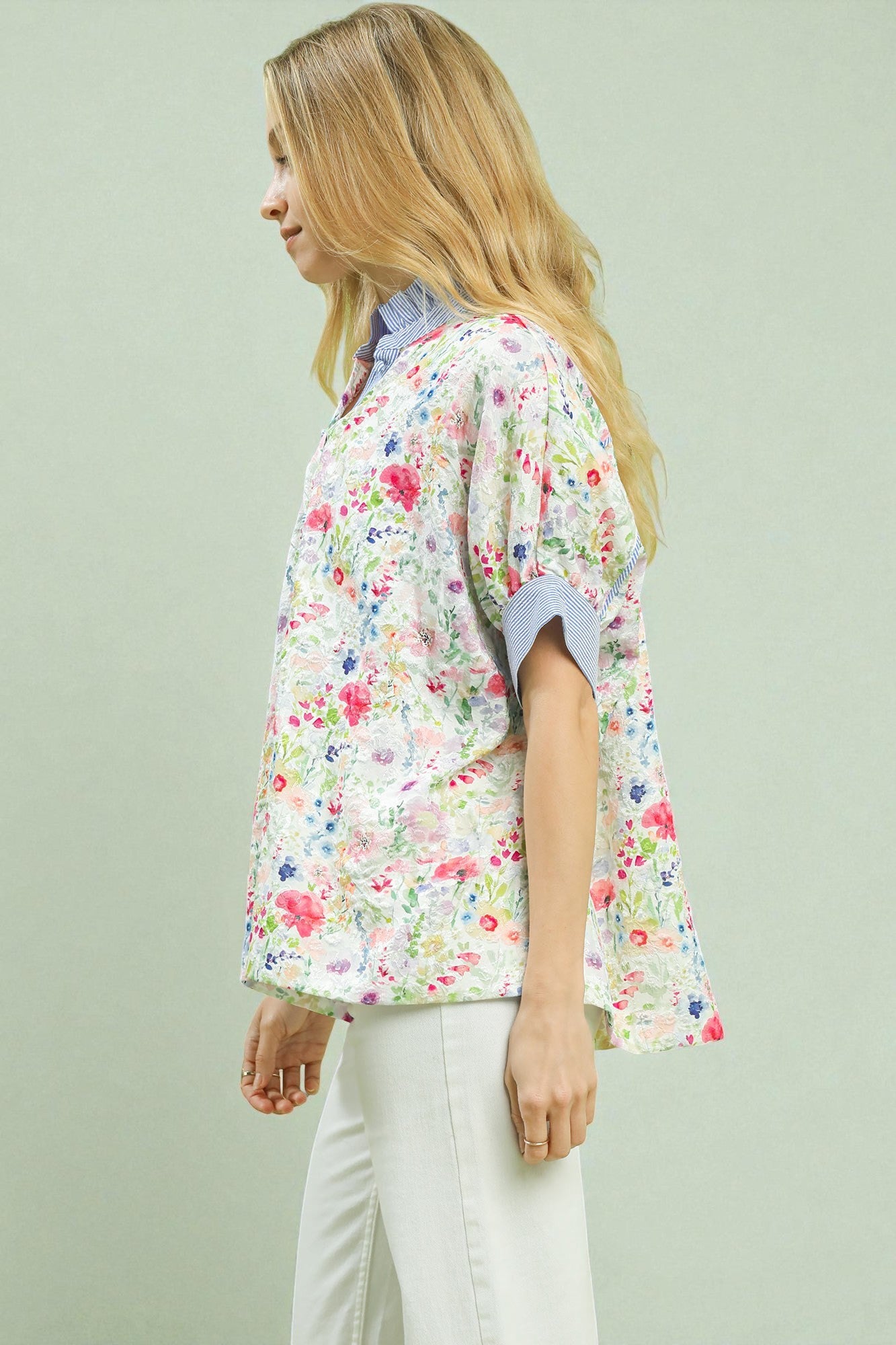 Woman wearing a floral kimono-style top against a light green background