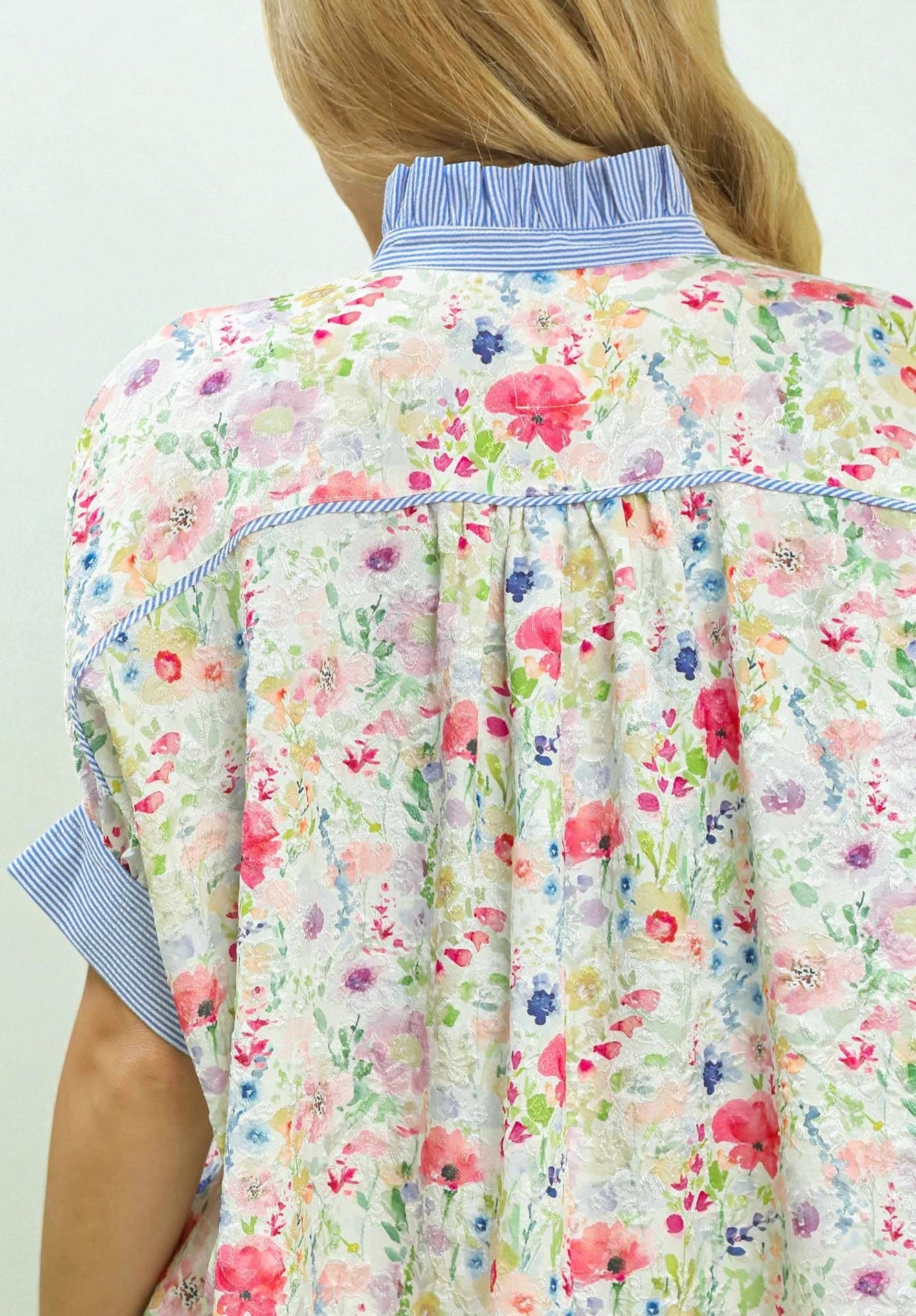 Floral-patterned apron over a person wearing a blue shirt on a white background