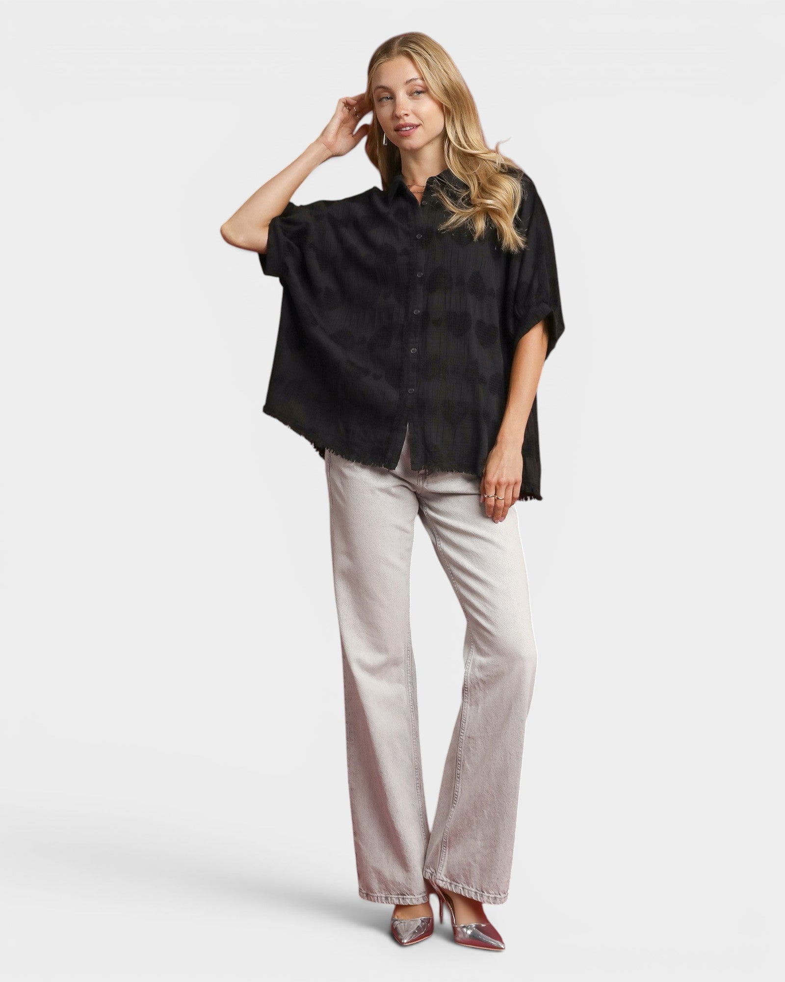 Woman wearing a black shirt and light-colored pants on a white background