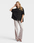 Woman wearing a black shirt and light-colored pants on a white background