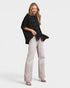 Woman wearing a black shirt and light-colored pants on a white background