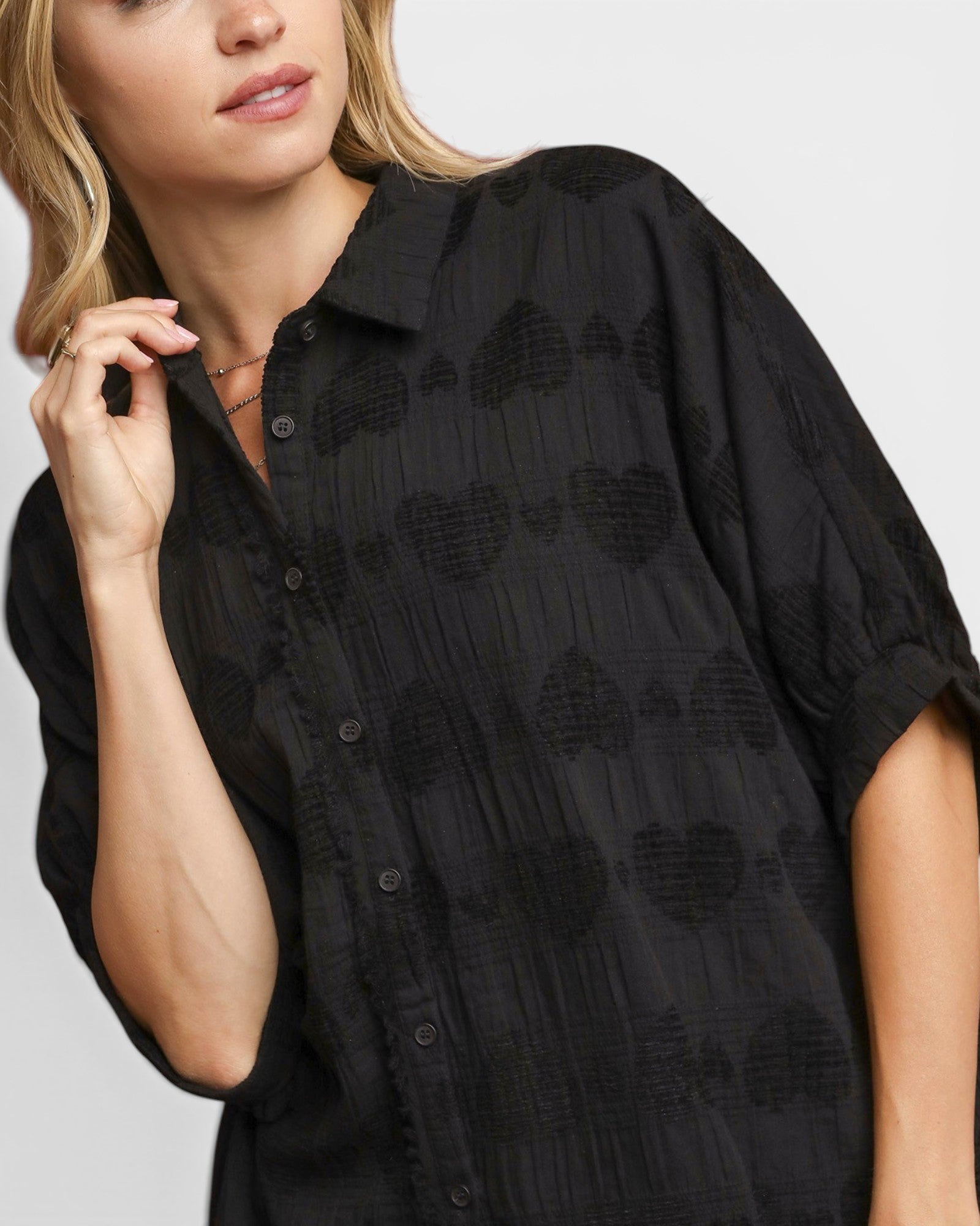 Woman wearing a black patterned shirt against a plain background