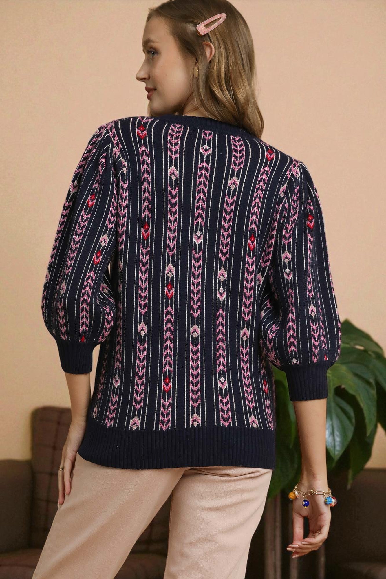 Person wearing a patterned sweater with a beige background