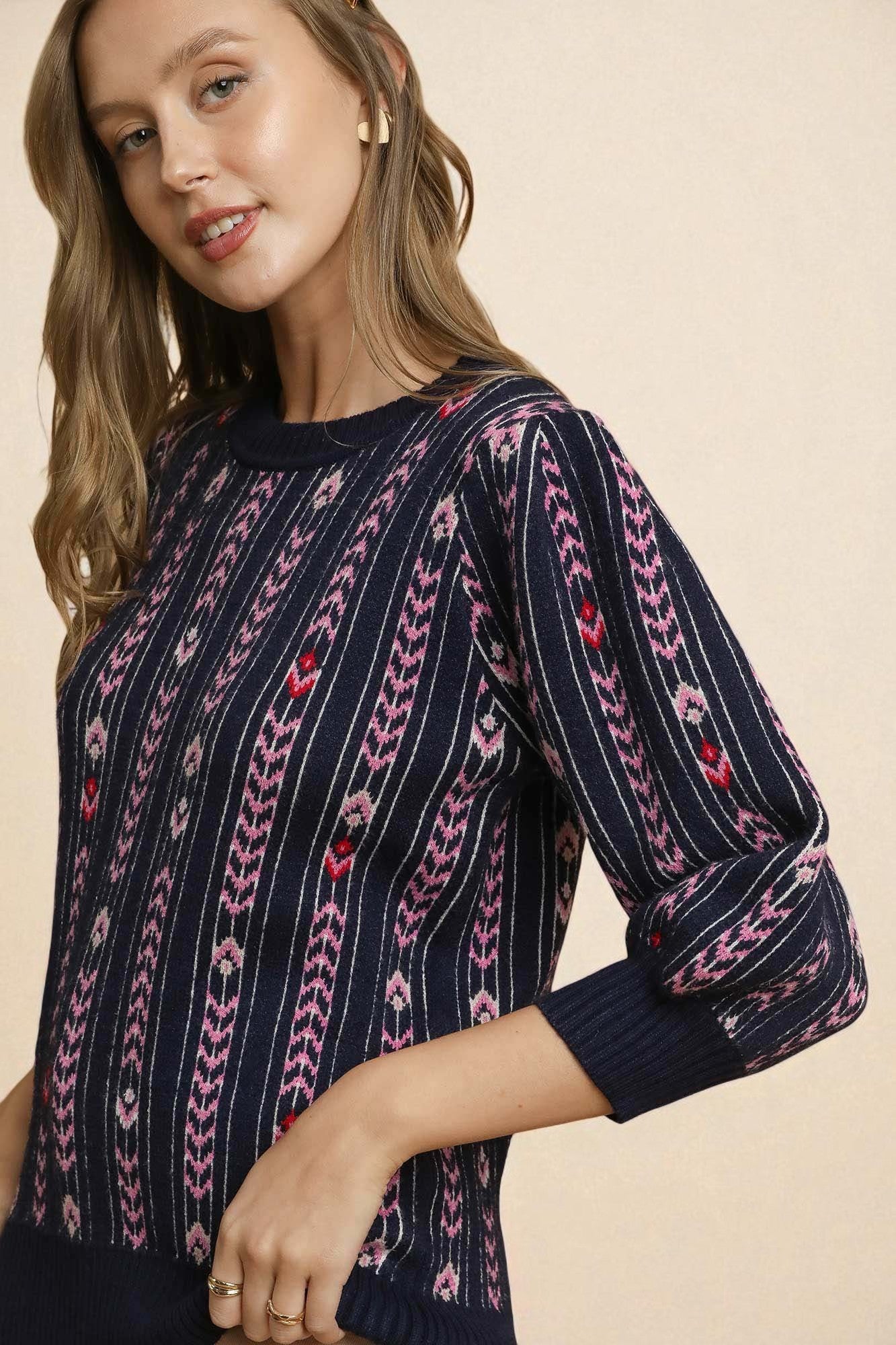 Woman wearing a navy sweater with pink and red pattern on a beige background