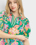 Woman wearing a colorful floral patterned shirt on a white background
