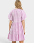 Woman wearing a pink dress with a white pattern on a white background
