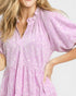 Woman wearing a light purple dress with a subtle pattern on a plain background