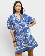 Woman wearing a blue and white patterned dress on a white background
