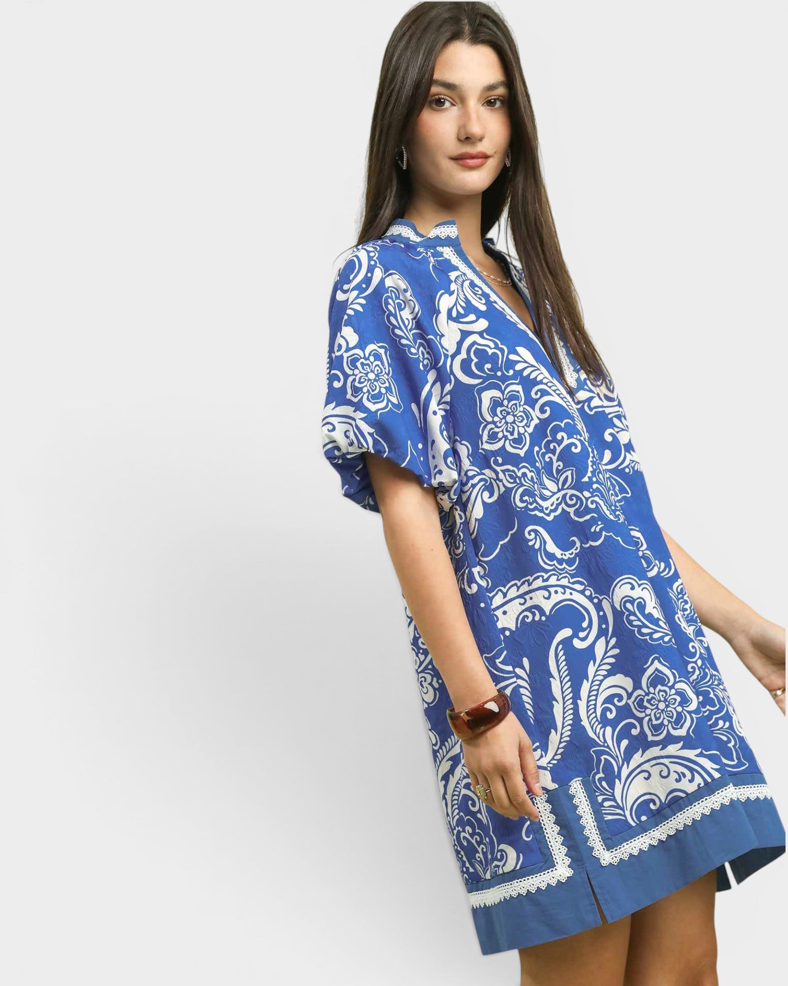 Woman wearing a blue and white patterned dress on a light gray background