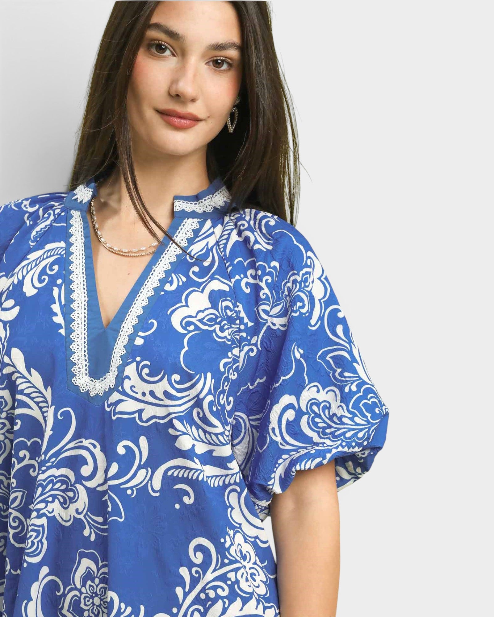 Woman wearing a blue and white patterned blouse on a plain background