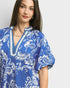 Woman wearing a blue and white patterned blouse on a plain background