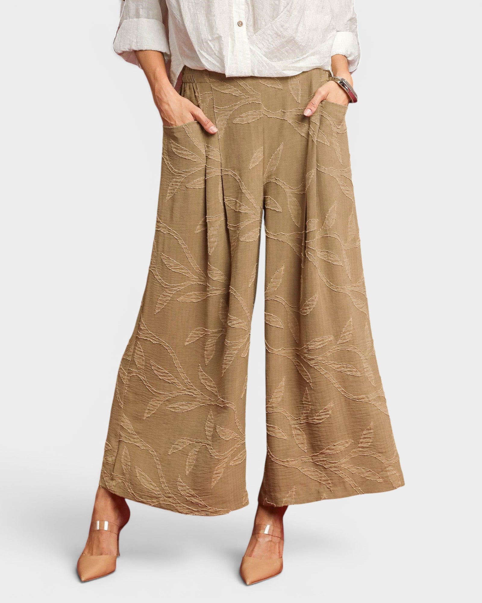 Person wearing beige patterned wide-leg pants on a white background