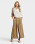 Woman wearing a white blouse and beige wide-leg pants on a white background