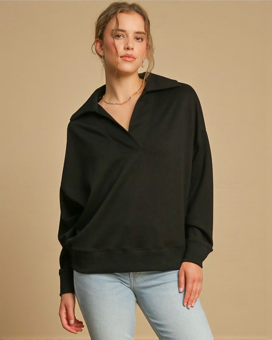 Woman wearing a black sweater and light blue jeans against a beige background