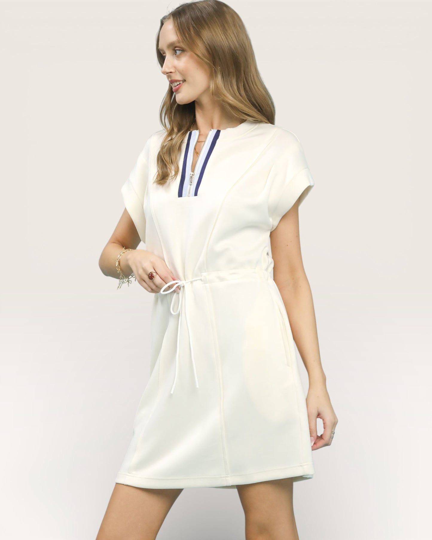Woman wearing a white dress with a blue and red trim on a plain background