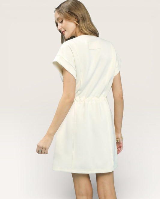 Woman wearing a light-colored dress against a plain background