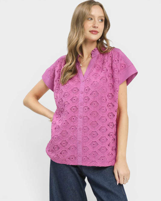 Woman wearing a pink lace top against a white background