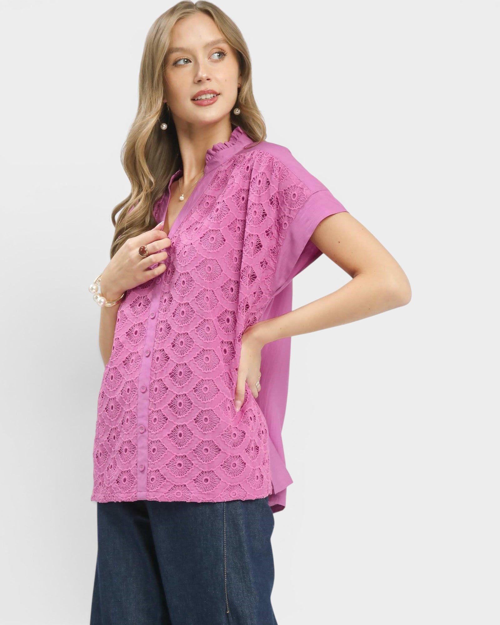Woman wearing a pink lace top and blue pants on a white background