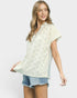 Woman wearing a light-colored lace top and denim shorts on a plain background