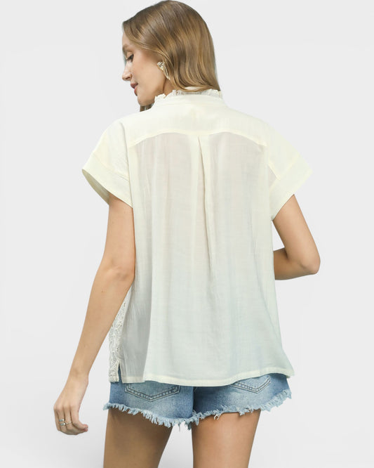 Woman wearing a light-colored blouse and denim shorts on a plain background
