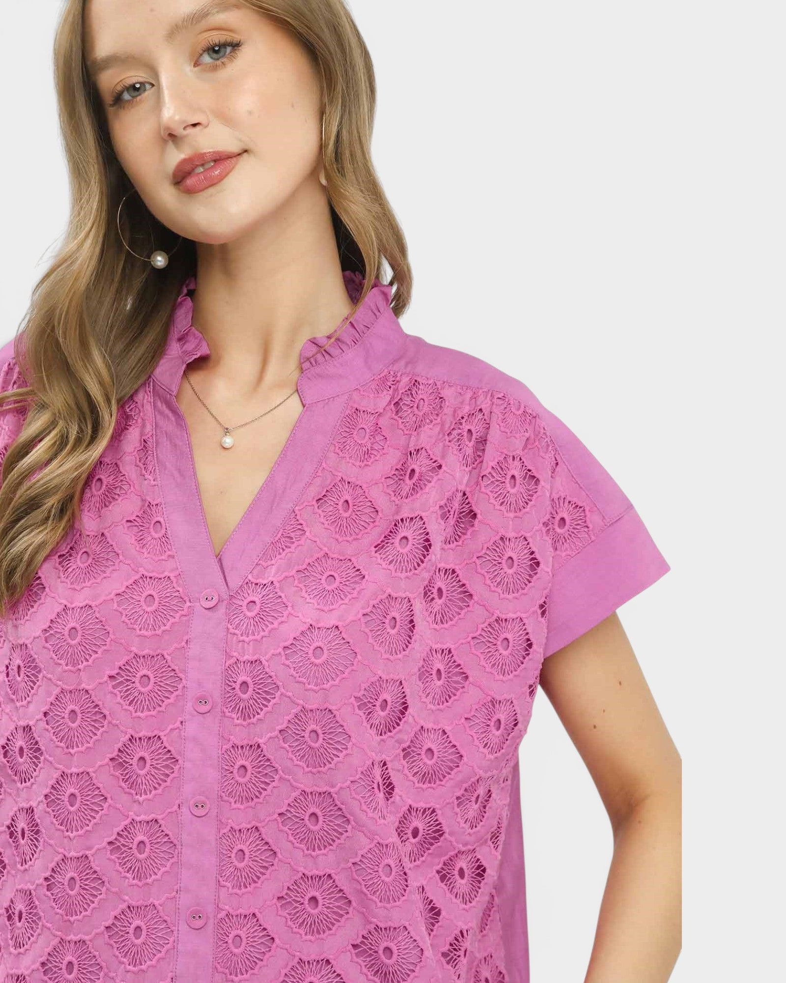 Woman wearing a pink lace blouse on a white background