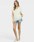Woman wearing a white lace top and denim shorts on a plain background