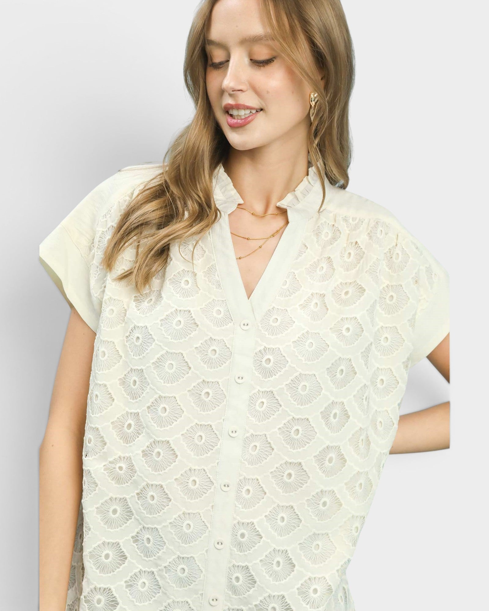 Woman wearing a white lace top against a plain background