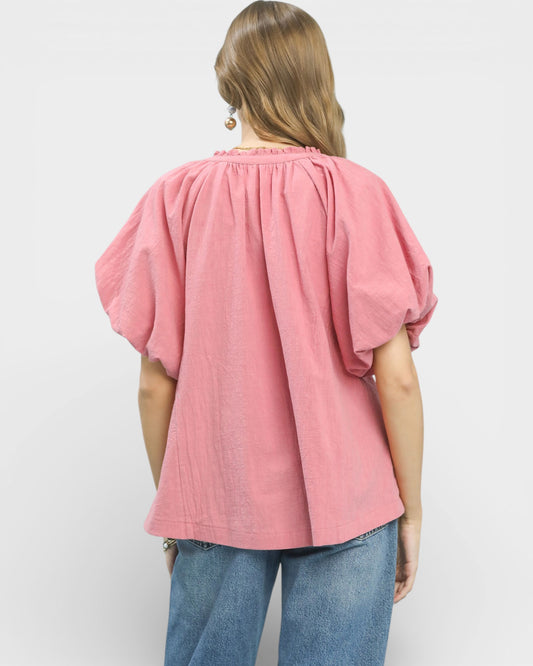Person wearing a pink blouse with balloon sleeves on a white background