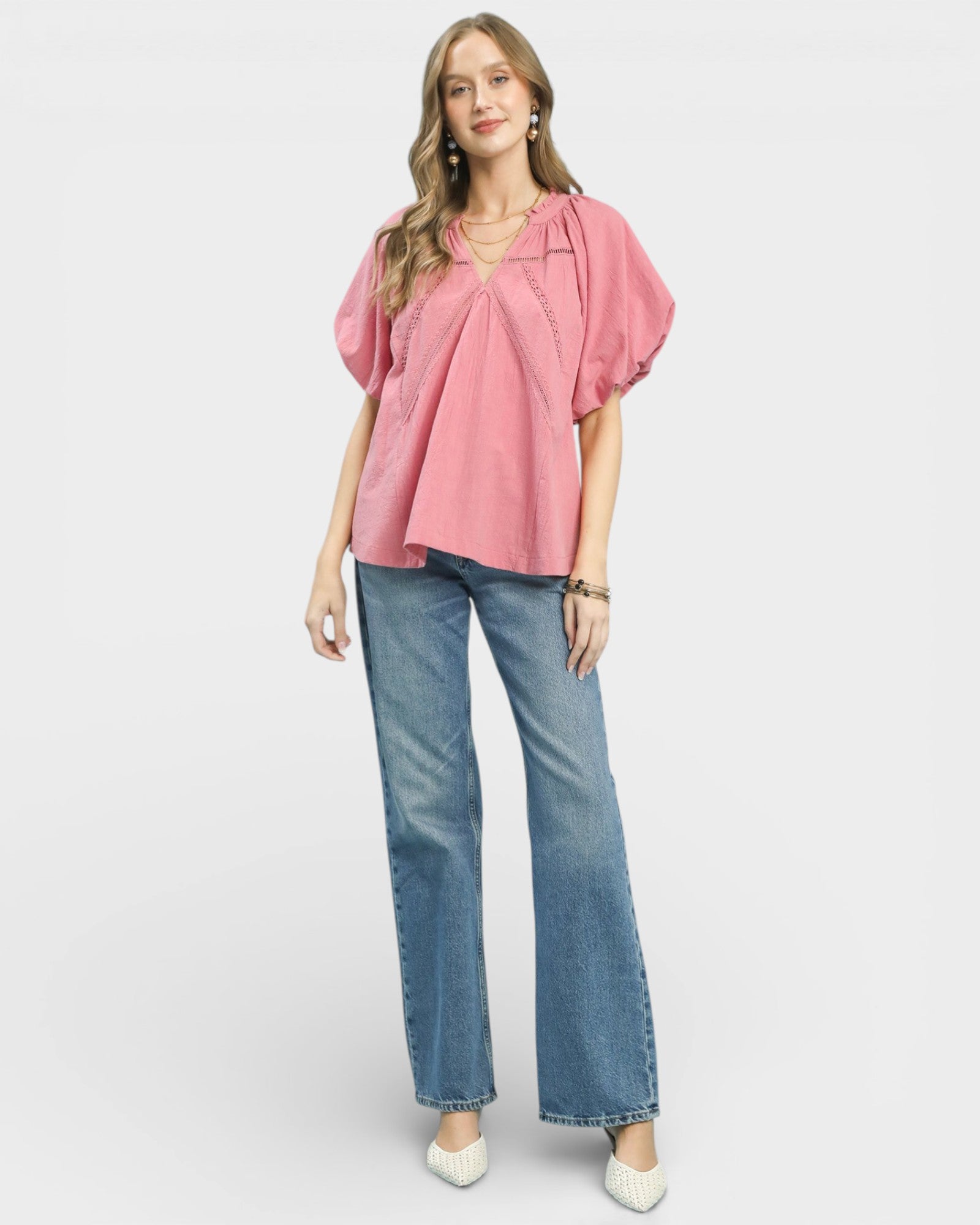 Woman wearing a pink blouse and blue jeans on a white background