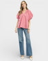 Woman wearing a pink blouse and blue jeans on a white background