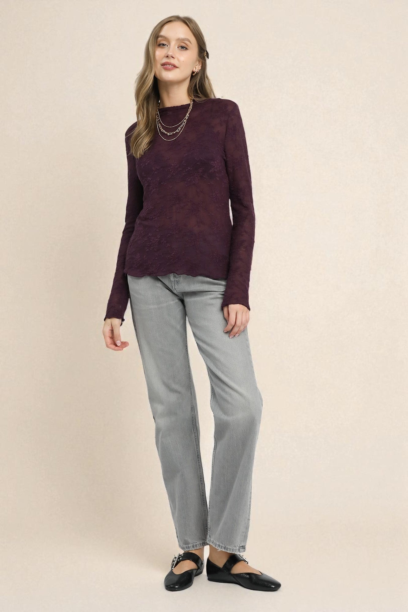 Woman wearing a purple sweater and gray pants on a beige background