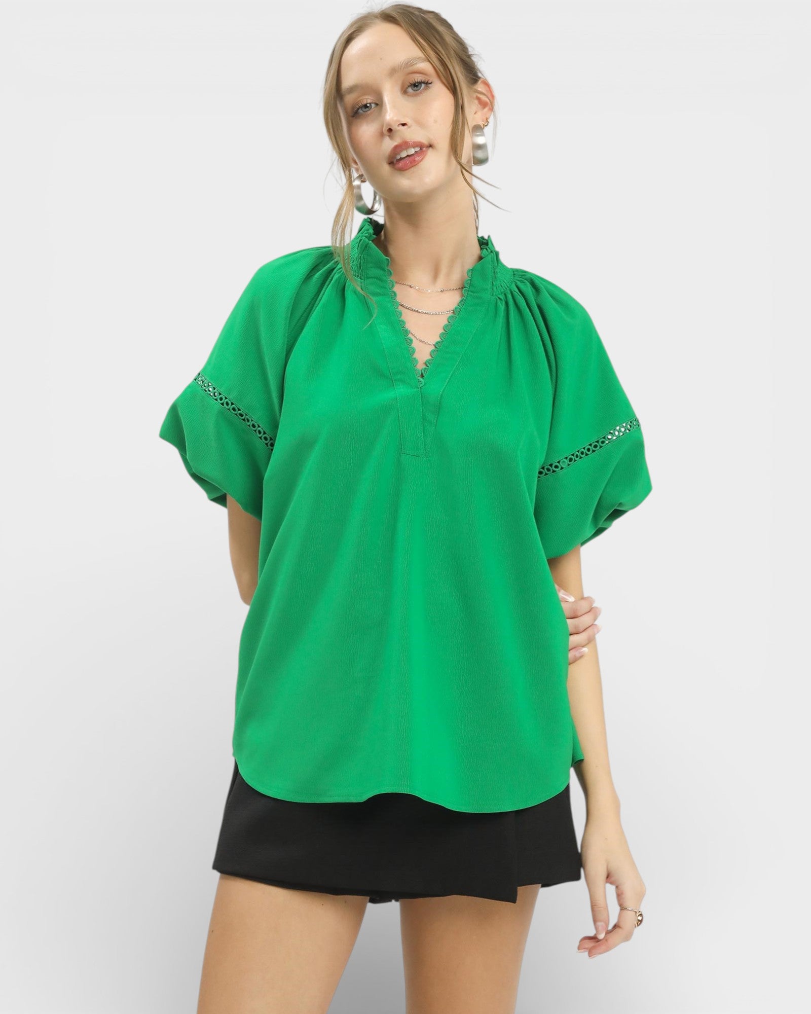 Woman wearing a green blouse with black trim on a white background