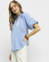 Woman wearing a light blue blouse with a plain background