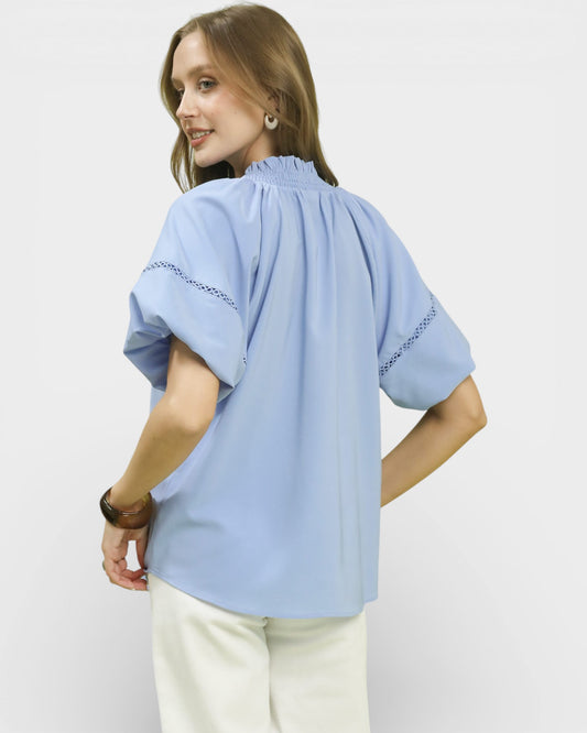 Woman wearing a light blue blouse with embroidered sleeves on a white background