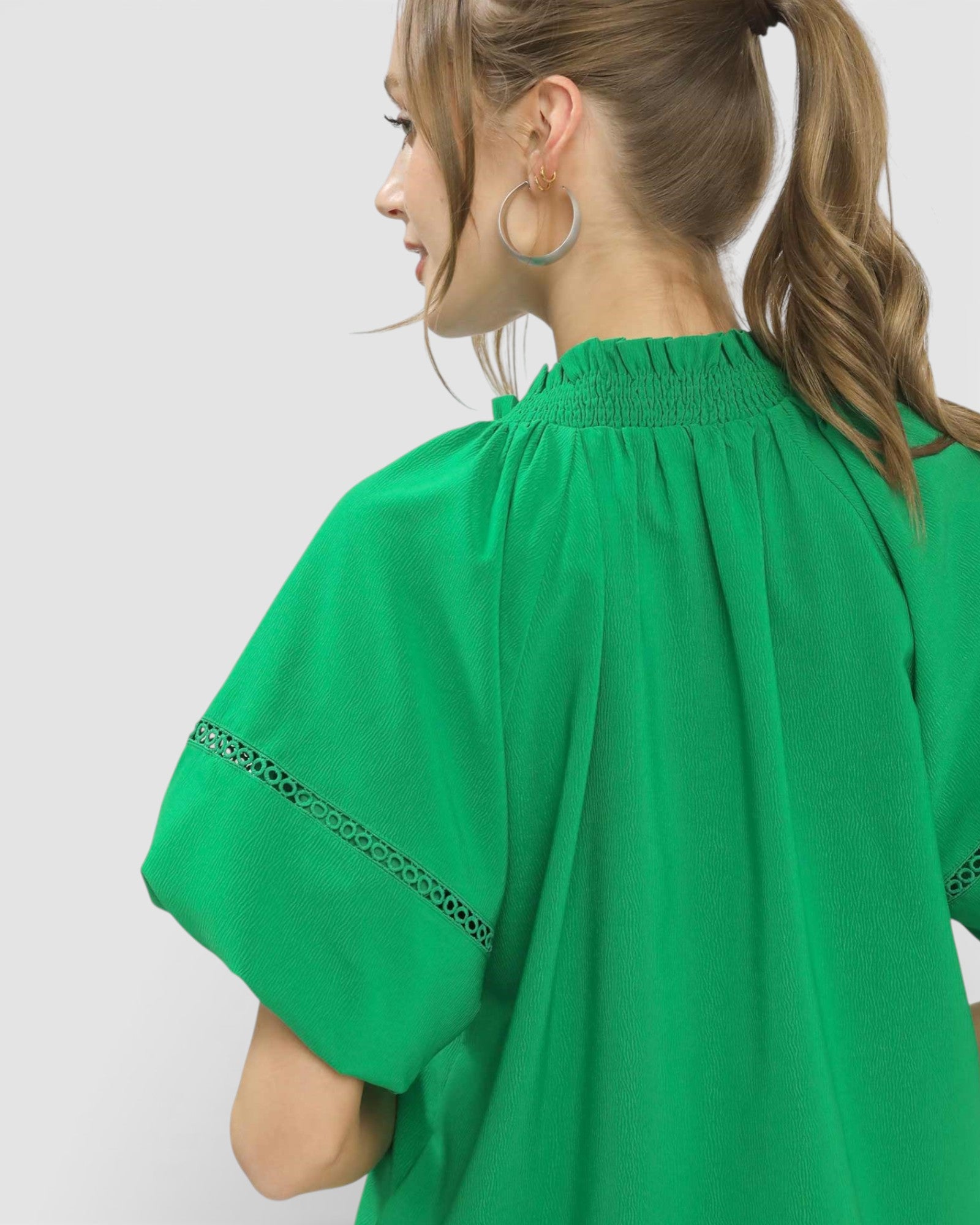 Green blouse with lace details on a plain background