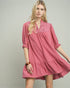 Woman wearing a pink dress with lace details on a plain background