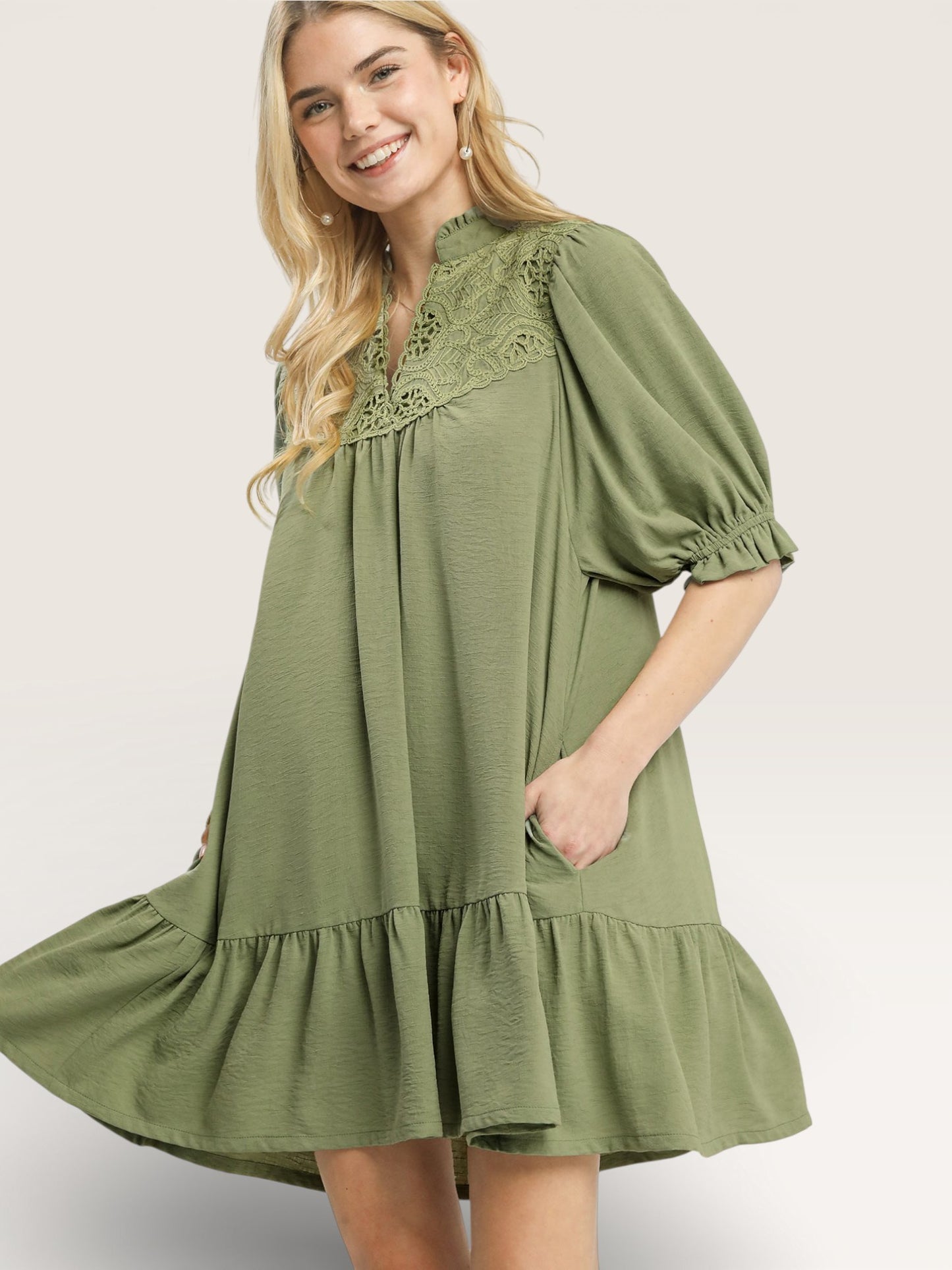 Woman wearing a green dress with lace details on a white background