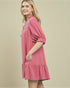 Woman wearing a pink dress with lace details on a beige background