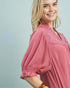 Woman wearing a pink dress with lace details on a light gray background