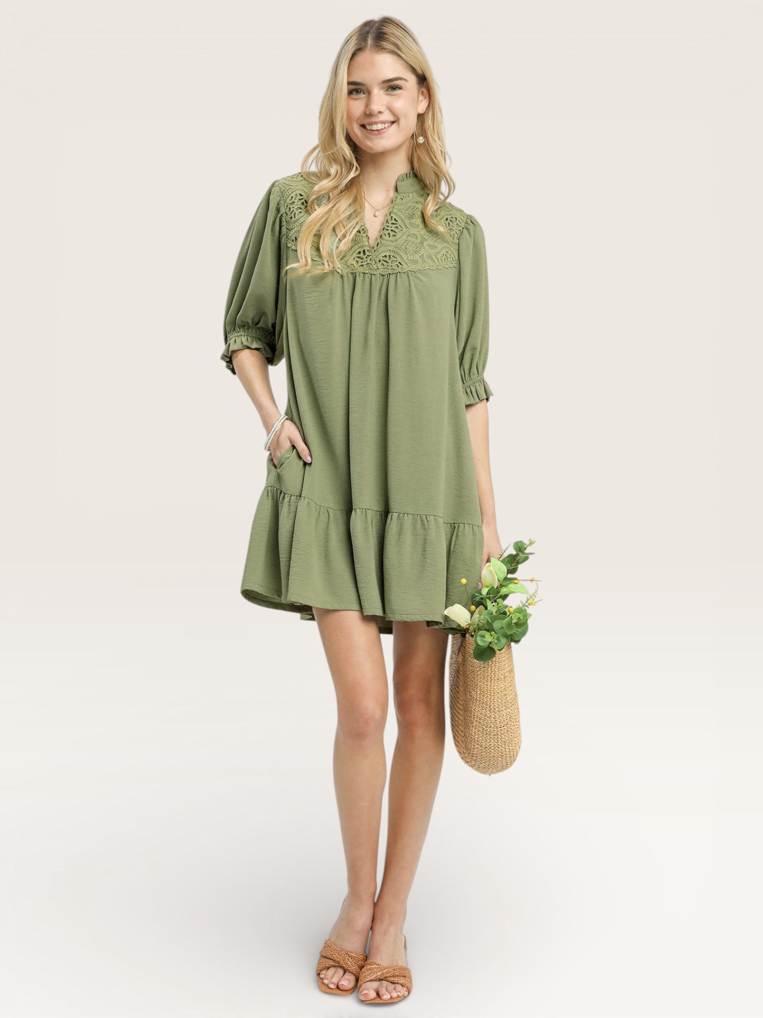 Woman wearing a green dress holding a woven bag on a white background