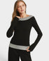 Woman wearing a black sweater with gray trim on a white background